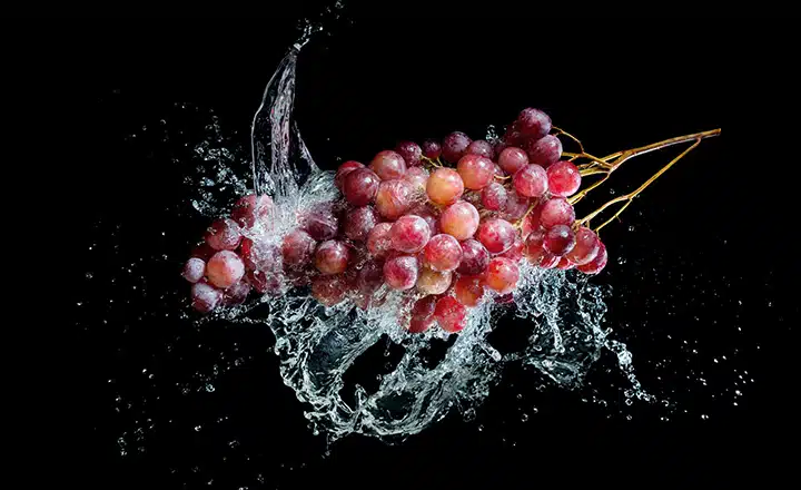 Bunch of grapes in water splash on black background