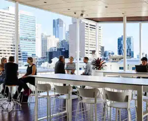 People working on the rooftop of a building with a Brisbane skyline 