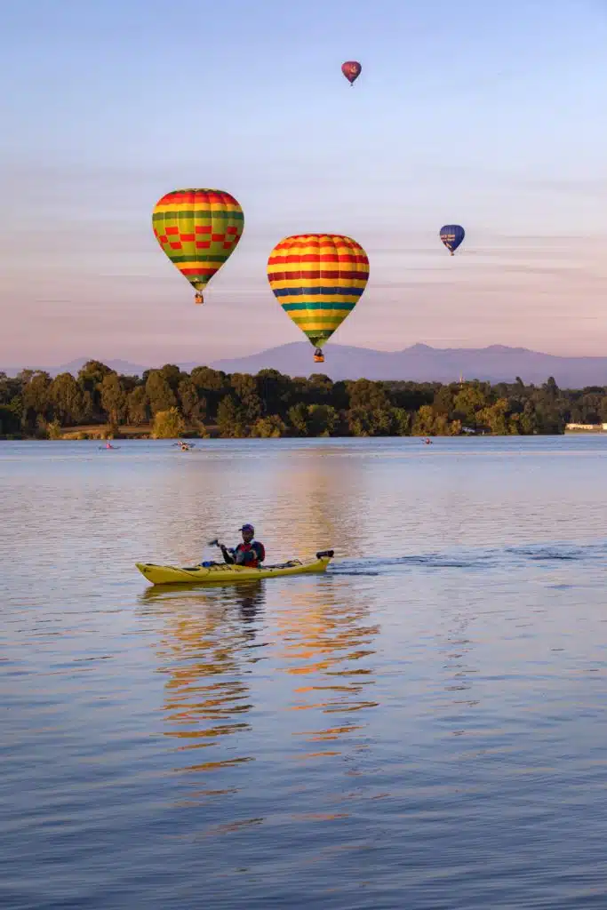 A lake in Canberra with hot water balloons passing over