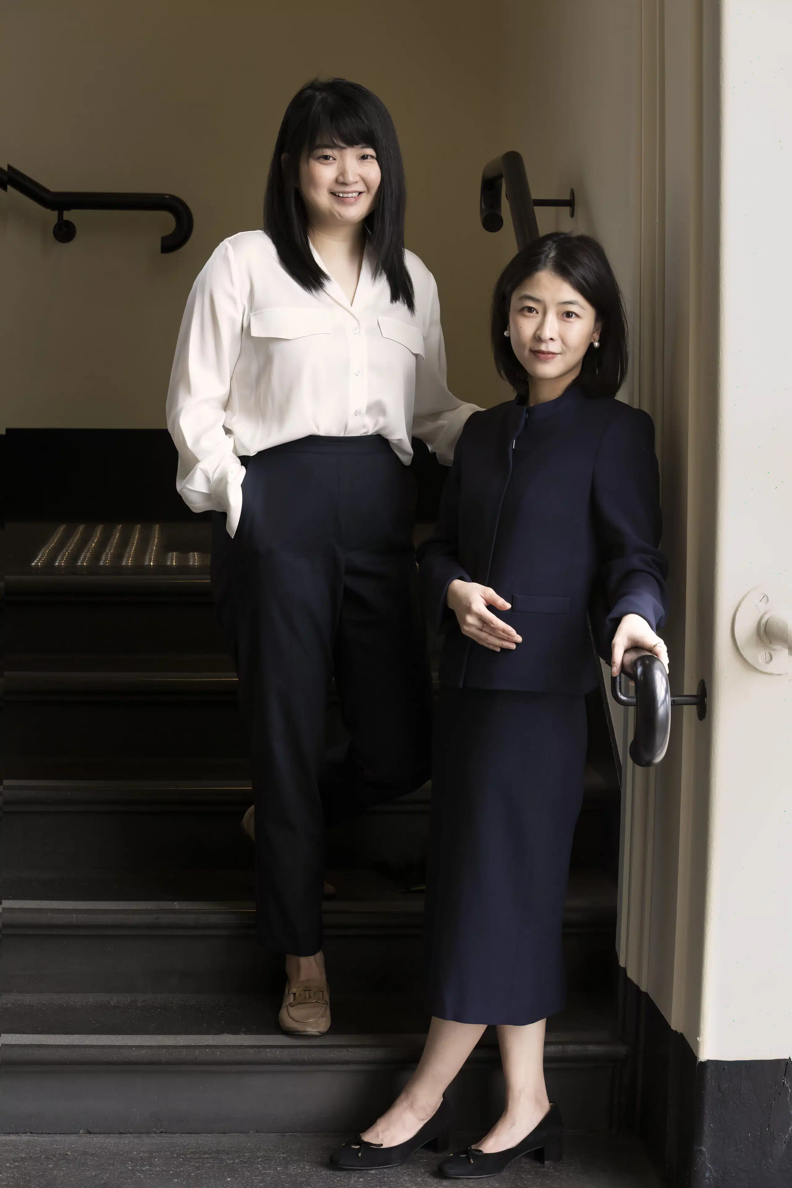 two women in monochrome clothing standing on stairs