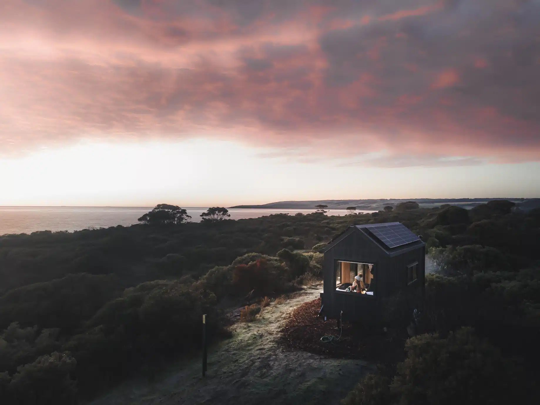 Girl inside an Unyoked cabin near the beach during sunset